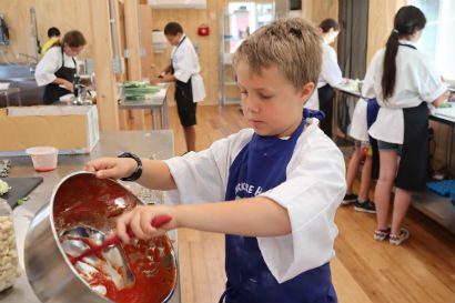 A boy pouring batter into a bowl